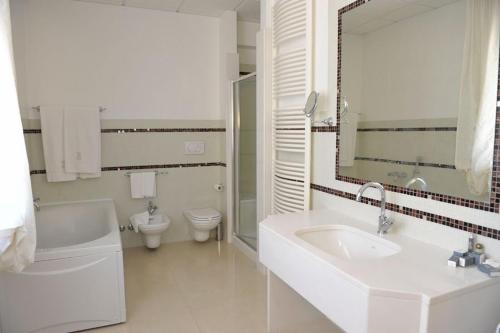 a white bathroom with a sink and a toilet at Hotel Svevo in Gioia del Colle