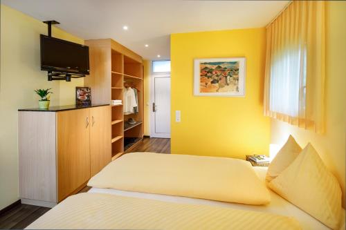 a yellow room with a bed and a tv at Seehotel Beinwil am See Swiss Quality in Beinwil