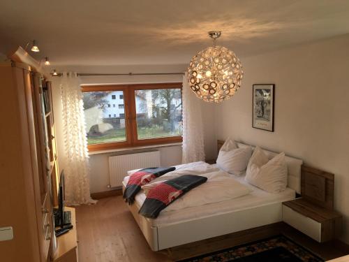 a bedroom with a bed with a chandelier and a window at Apartment Nockspitze in Innsbruck