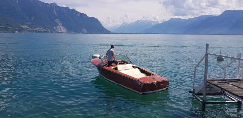 a man standing on a boat in the water at Montreux Rotana Garden House with Private Pool - Swiss Hotel Apartments in Montreux