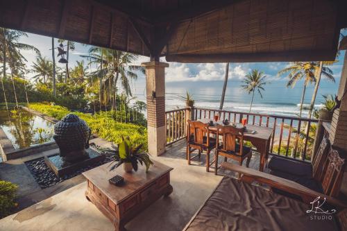 a porch with a table and a view of the ocean at Villa Rumah Pantai Bali in Selemadeg