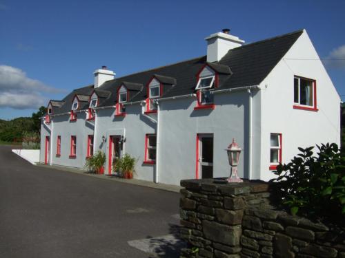 a large white building with red windows and a street at Reenmore Farmhouse in Ahakista