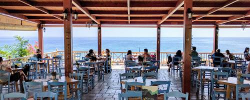 a restaurant with people sitting at tables on the beach at Gigilos in Agia Roumeli