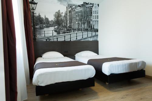 アムステルダムにあるバスティオン ホテル アムステルダム アムステルの壁に絵が描かれた部屋のベッド2台