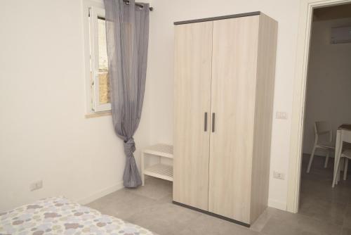 a bedroom with a large wooden cabinet next to a window at Sciabika Home - Edificio Eolie in Castellammare del Golfo