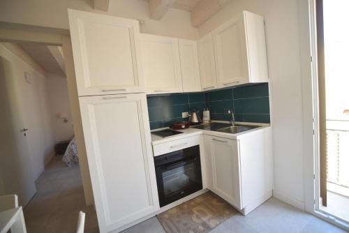 a small kitchen with white cabinets and a sink at Sciabika Home - Edificio Eolie in Castellammare del Golfo