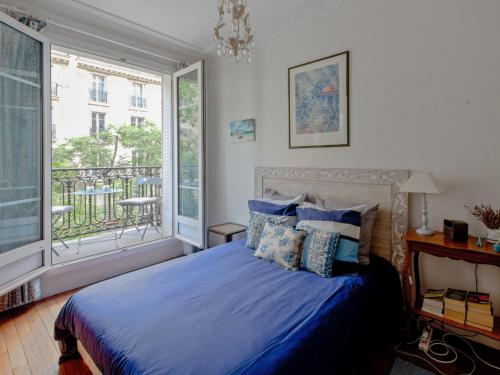 een slaapkamer met een blauw bed en een balkon bij Welkeys - Felix Faure in Parijs