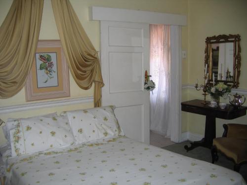 a bedroom with a bed and a table with a mirror at Villa Victoria executive Guest House in Benoni