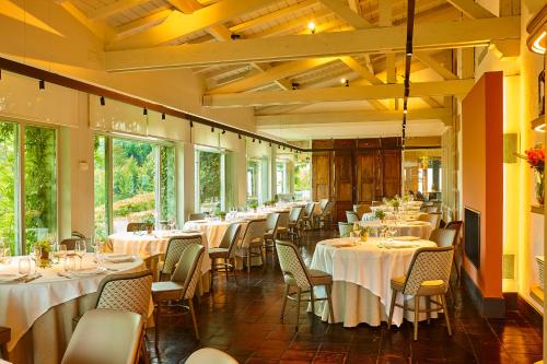 un restaurante con mesas y sillas blancas y ventanas en Hotel Palacio Urgoiti, en Mungia