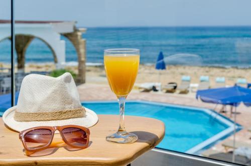 a straw hat and sunglasses and a glass of orange juice at Pyrgos Blue in Malia