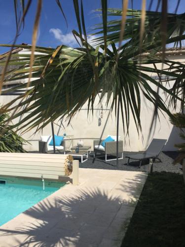 une piscine avec des chaises longues et un palmier dans l'établissement La Maison du Baloir, à Thairé