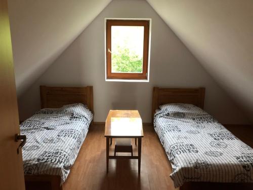 a attic room with two beds and a table at Szent Ilona Vendégház in Monoszló