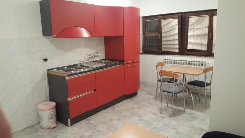 una cocina con armarios rojos y una mesa. en Apartmani Košuta, en Tjentište