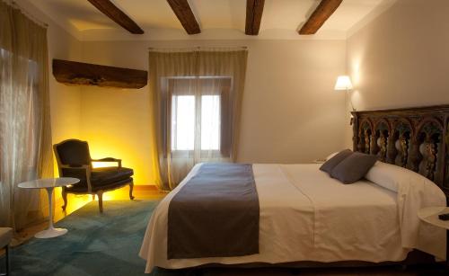 sypialnia z łóżkiem, krzesłem i oknem w obiekcie Hospederia Chapitel w mieście Estella