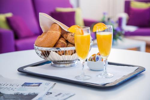 a tray with two glasses of orange juice and bread at Tertianum Residenza Al Lido - Appartements & Restaurant in Locarno