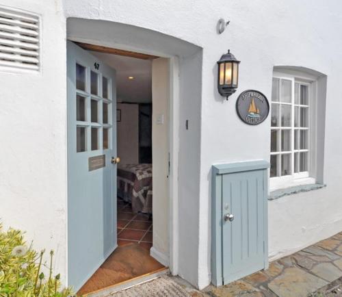 a white house with a blue door and a window at Shipwrights Cottage in Salcombe