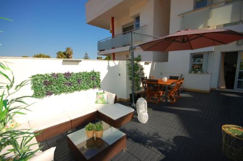 エル・カンページョにあるGran terraza Muchavista San Juan Alicanteのパティオ(ソファ、パラソル、テーブル付)
