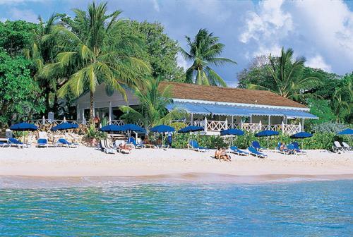 a beach with blue umbrellas and people sitting on the beach at Coconut Grove 8 Luxury Villa by Island Villas in Saint James
