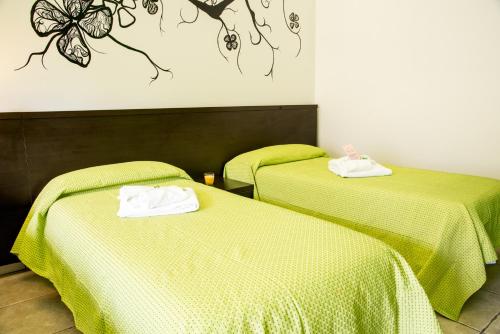 two beds in a room with green sheets at Guest House Park in Valmontone