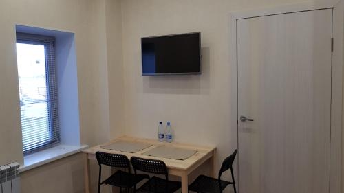 オムスクにあるApartamenty "Izumrud"のテーブル、椅子、壁掛けテレビが備わる客室です。