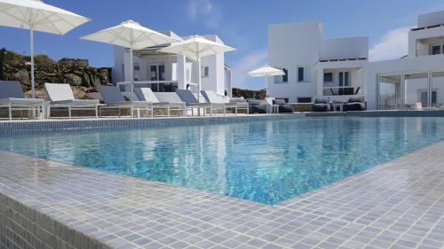 a swimming pool with white chairs and umbrellas at Lemon Tree Houses in Ano Meria