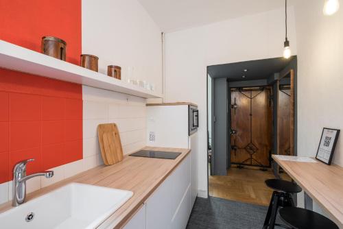 een keuken met een wastafel en een rode muur bij Honorê - Suite Trois Maries in Lyon