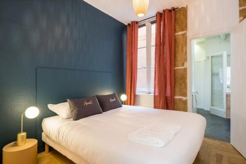a bedroom with a white bed and a blue wall at Honorê - Suite Trois Maries in Lyon