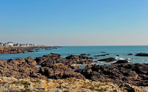 a group of rocks on the beach with the ocean at Résidence Le Vénète in Le Croisic