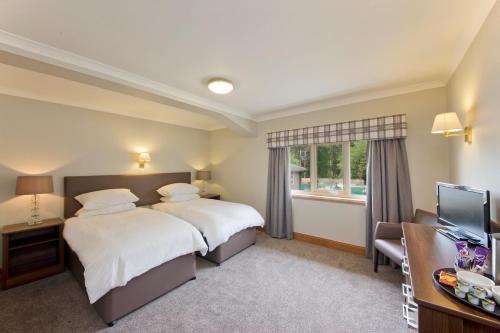 um quarto de hotel com duas camas e uma televisão em Tyndrum Lodges em Tyndrum