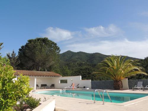 ein Schwimmbad mit einem Haus und Bergen im Hintergrund in der Unterkunft Mas Les Romarins in Montesquieu