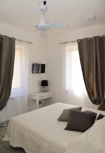 a bedroom with a white bed and two windows at B&B Casa Gaia in Città della Pieve