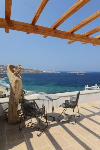 a patio with a table and chairs and the ocean at Legacy Suites in Mýkonos City