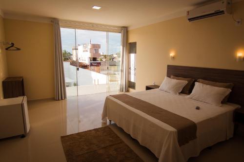 a bedroom with a large bed and a large window at ROYAL Hotel & Gastronomia in Macapá