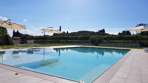 a large swimming pool with two chairs and umbrellas at Residenza Angelica in Lazise