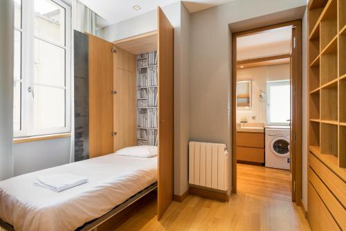 ein kleines Schlafzimmer mit einem Bett und einem Fenster in der Unterkunft Honorê - Suites Bellecour in Lyon