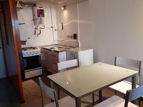 cocina con mesa blanca, mesa y sillas en Departamento Loft VCP en Villa Carlos Paz