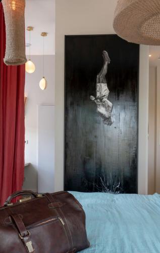 a bag sitting on a bed with a painting on the wall at Domaine Tarbouriech, Demeure & Spa in Marseillan