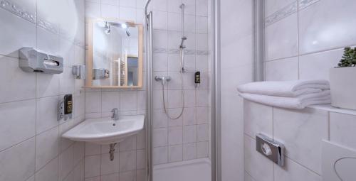 ein weißes Bad mit einer Dusche und einem Waschbecken in der Unterkunft Haus Fabry in Hilden