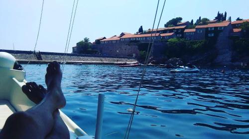 a person is waving from a boat in the water at Apartments Dragišić in Sveti Stefan