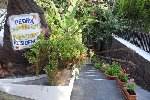 a garden path with potted plants and a sign at Pedra Residence in Stromboli