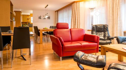 a living room with a red chair and a table at Haus Alpenglück in Saas-Fee