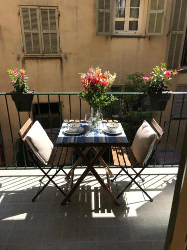 una mesa y sillas en un balcón con flores en Studio Chateau - Vieux Nice, en Niza