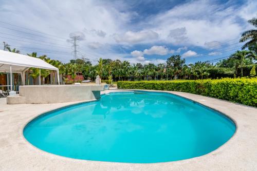 a large blue swimming pool in a yard with a pavilion at Hotel Pacuare in Siquirres