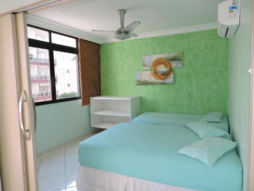 a bedroom with a blue bed with a green wall at Condomínio Lester Primo in Guarujá