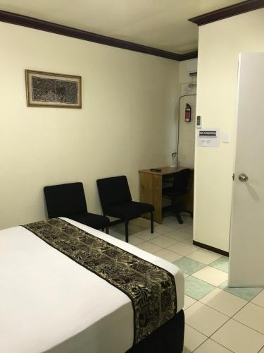 a bedroom with a bed and two chairs and a desk at Moatoga Hotel in Apia