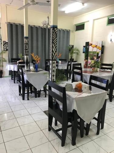 a dining room with white tables and chairs at Moatoga Hotel in Apia
