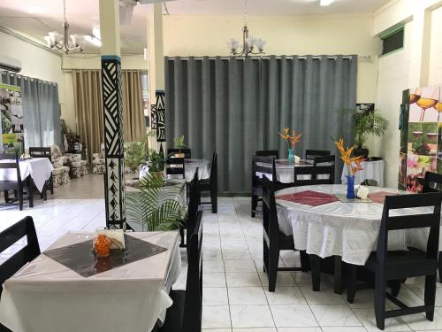 a dining room with tables and chairs and curtains at Moatoga Hotel in Apia