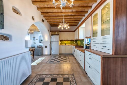 a large kitchen with white cabinets and a wooden ceiling at Blue Serenity Villa in Fanari