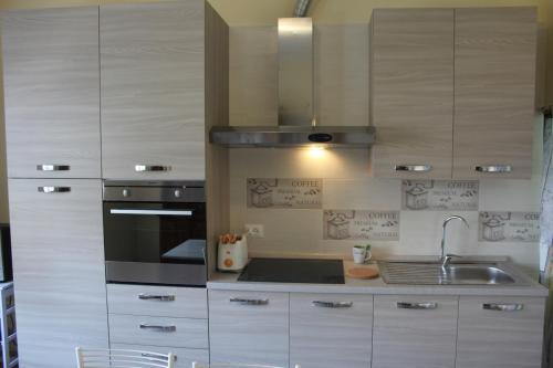 een keuken met witte kasten, een wastafel en een fornuis bij Brezza di Lago in Salò