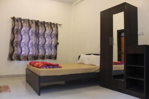 a small bedroom with a bed and a mirror at Malhar Bungalow in Panchgani